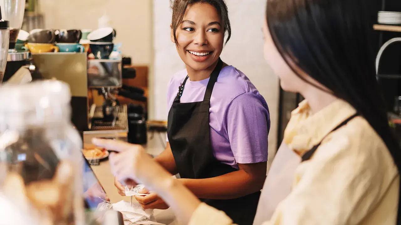 two women at a cash register of a cafe