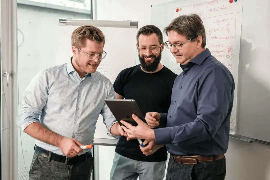 Drei Personen sitzen am Tisch mit ihren Laptops mit SIGN IT für Italien