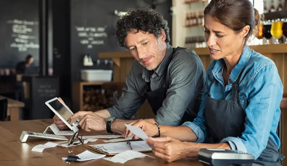 A middle-aged man and woman calculating invoices for their restaurant business