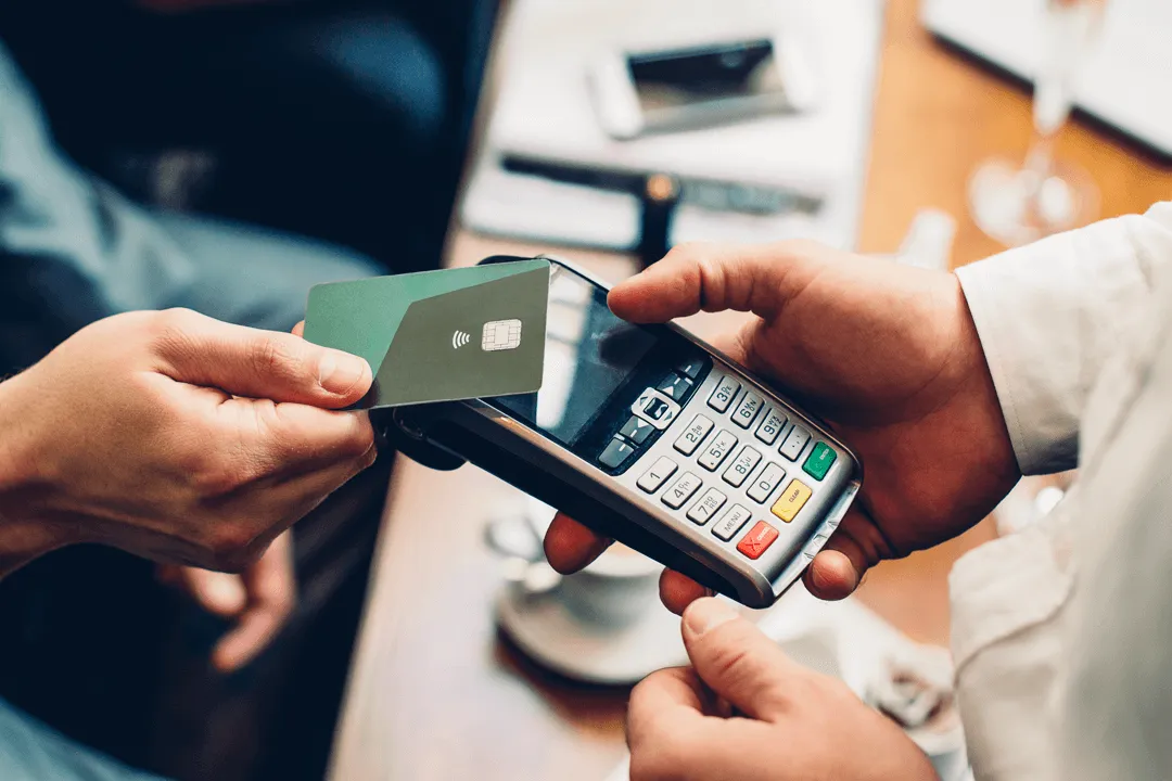 A hand paying with a card on a payment terminal.