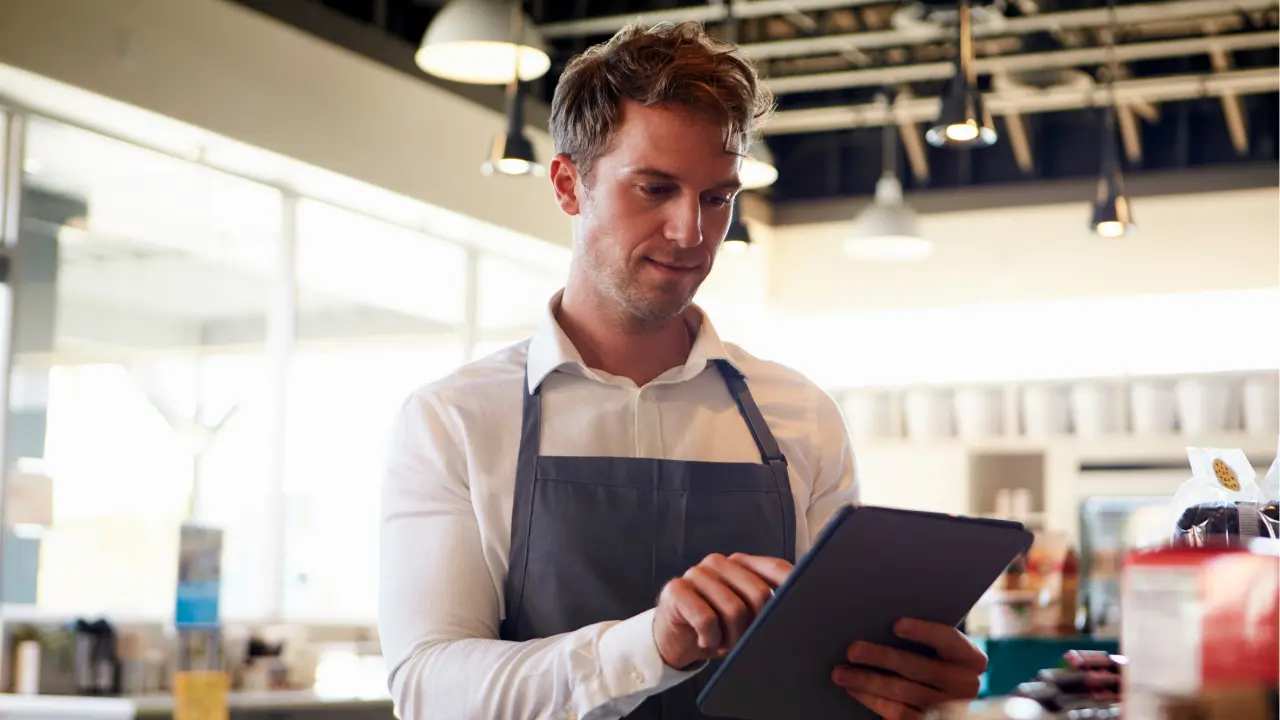 A man working at a café in France, using a certified POS system that is fully compliant with French fiscal law.