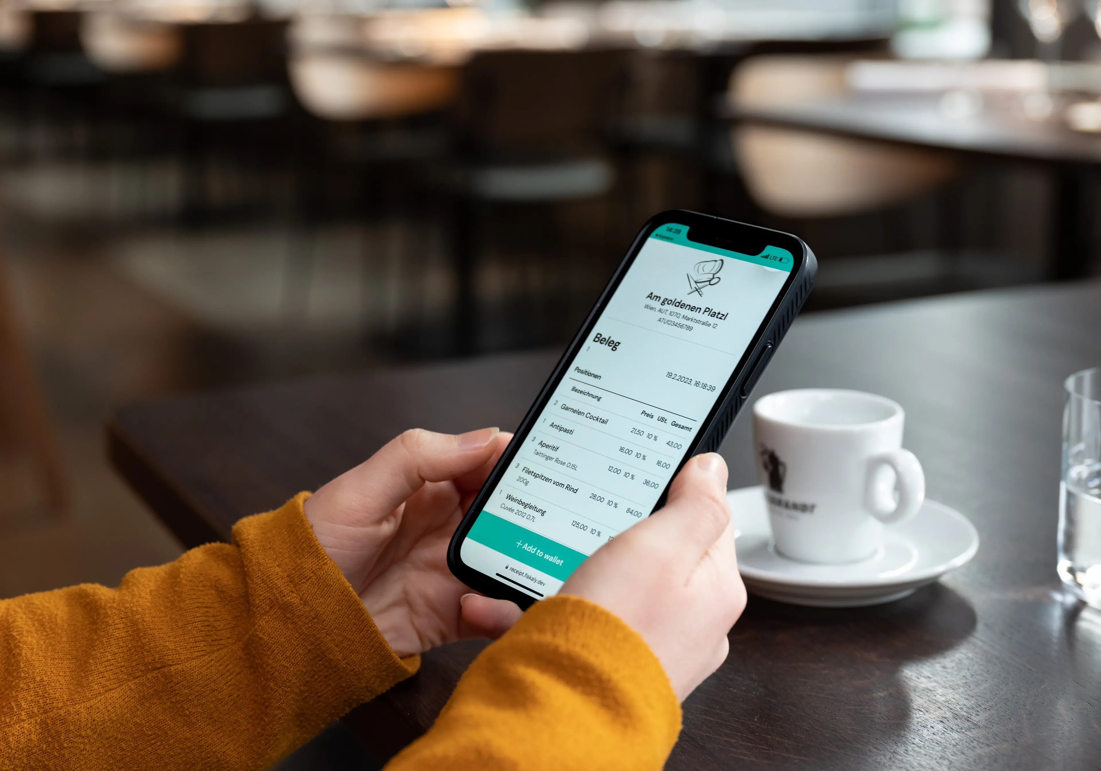 Woman's hands in an orange sweater, holding a cell-phone with an e-receipt on it